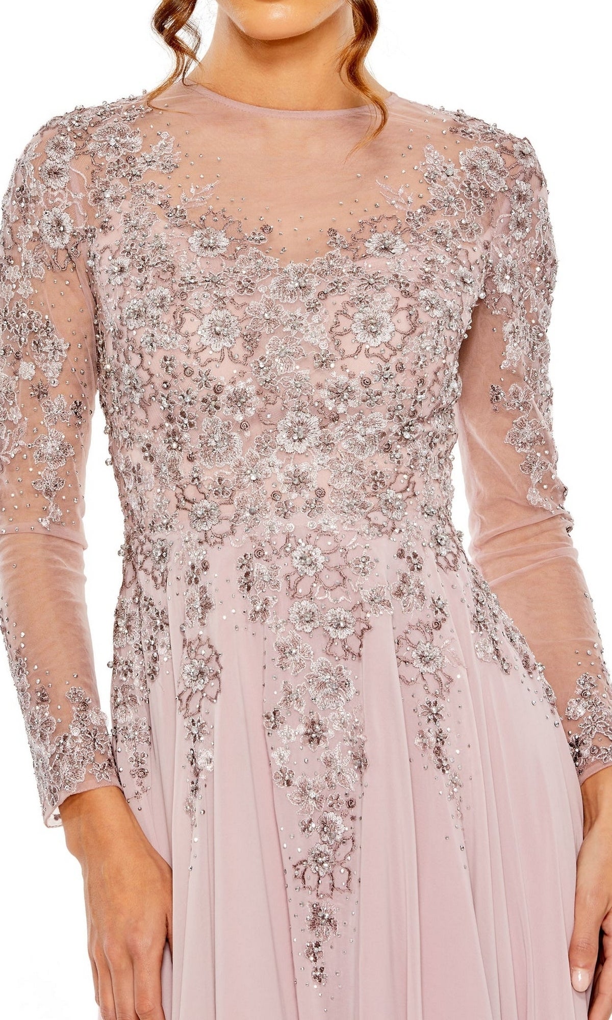 A woman wears the Mac Duggal 20478, a long-sleeved light pink formal A-line dress with silver floral embroidery and beadwork, standing against a white background.